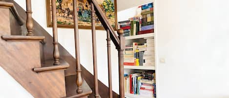 Una escalera de madera con un cuadro encima y una estantería llena de libros.