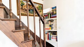 A wooden staircase with a painting above it and a bookshelf filled with books. - Lovely Apartment Near the Eiffel Tower (Paris)