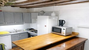 Une cuisine avec des meubles de couleur grise, un réfrigérateur blanc, un four à micro-ondes et un plan de travail en bois.
