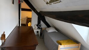 Une pièce avec un plafond en pente, un bureau en bois, un lit avec un cadre en bois et une petite table avec une lampe.