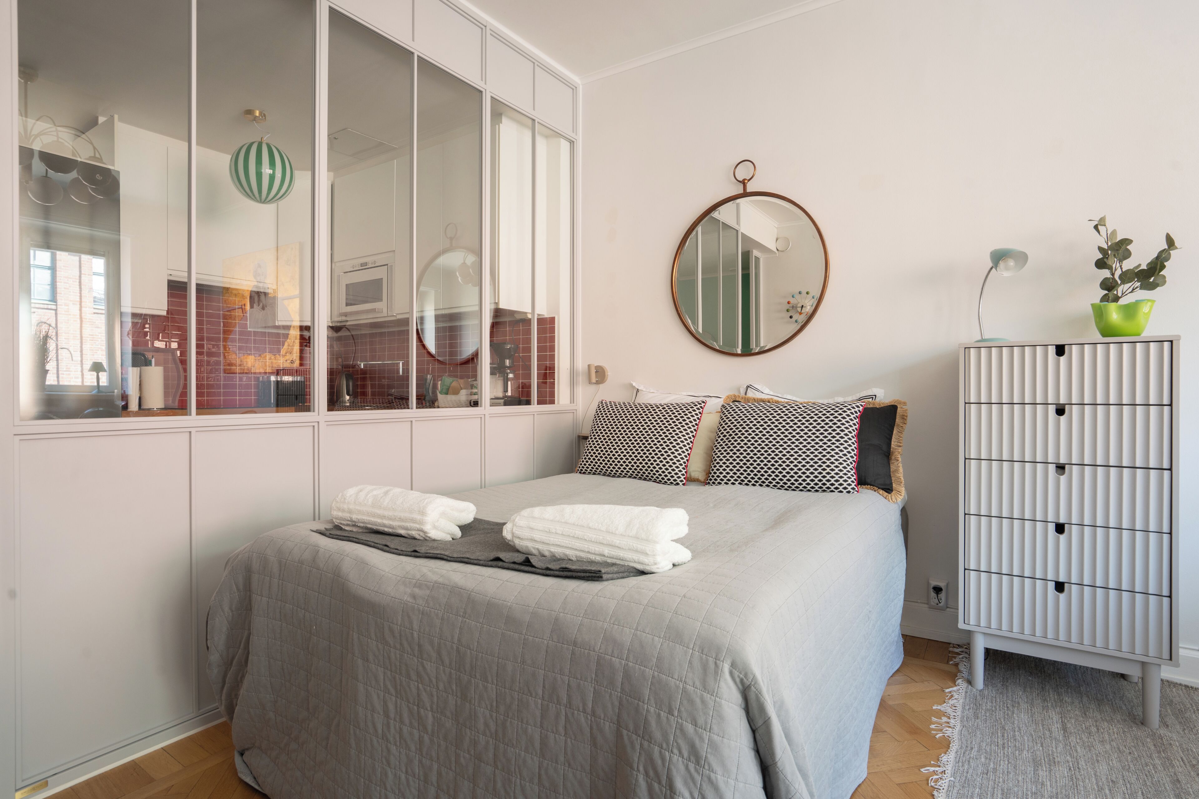 Una camera da letto con un letto, un armadio, uno specchio e una pianta in vaso.