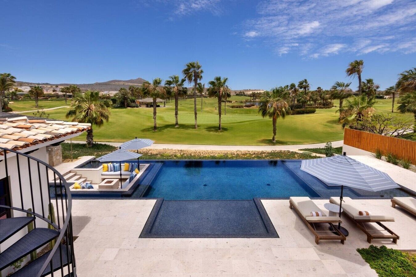 Piscina con sillas de descanso y vista a un campo de golf.