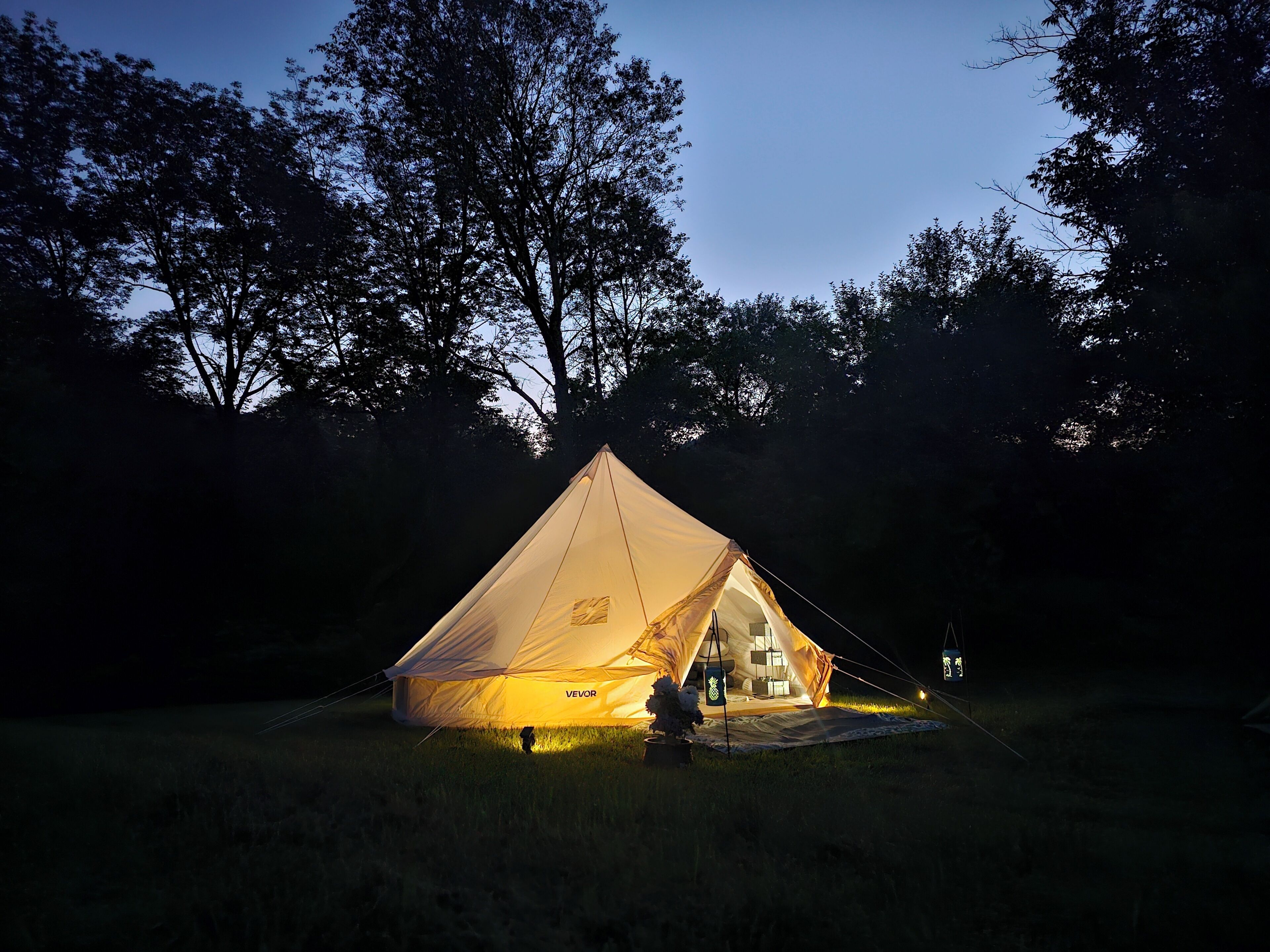 A tent with a visible brand name, set up in a grassy area with trees in the background.