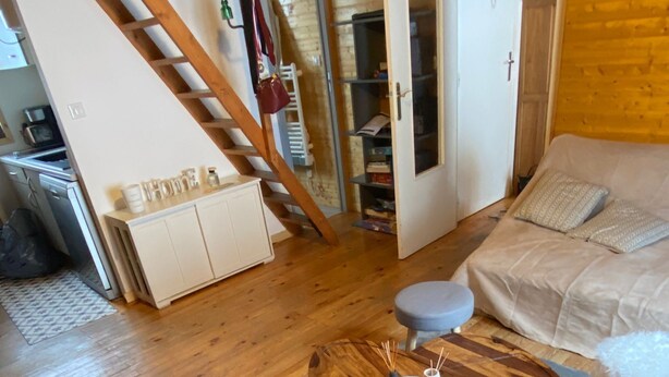 Ett mysigt vardagsrum med ett matbord i trä, en soffa och en trappa som leder till ett annat rum.