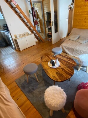 Un salon chaleureux avec une table à manger en bois, un canapé et un escalier menant à une autre pièce.