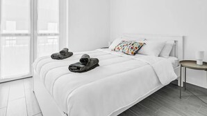 Een hotelkamer met een groot bed, een kleine tafel en uitzicht door een glazen deur.