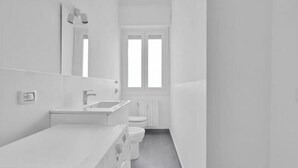 Een moderne badkamer met een grote spiegel, een wastafel en een toilet.