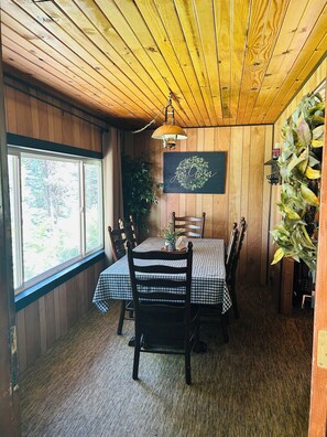 A dining area with a wooden ceiling, a table with checkered tablecloths, and chairs. - Family Friendly, Cozy 3-bedroom cabin in amazing Cascade with AC and Wood stove. (Cascade)