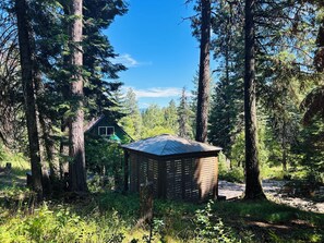 A cabin surrounded by tall trees in a forest. - Family Friendly, Cozy 3-bedroom cabin in amazing Cascade with AC and Wood stove. (Cascade)