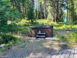 A wooden hot tub with a bench in a forested area. - Family Friendly, Cozy 3-bedroom cabin in amazing Cascade with AC and Wood stove. (Cascade)