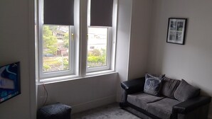 A room with a window, a radiator, a sofa, and two framed pictures on the wall. - 2nd Floor, Train Stn, Beach, Cumbrae-Millport Ferry Port All Under 0.3 Mile. (Largs)