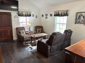 Ein Wohnzimmer mit einem braunen Ledersofa, einem Holztisch und einem Teppich mit Hunde-Motiv.