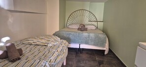 Une chambre avec deux lits, un mur vert et une tête de lit incurvée originale.