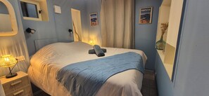 A bedroom with a bed, bedside lamp, and a poster on the wall.