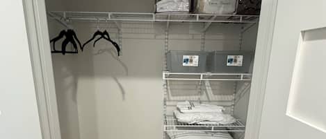 A closet with shelves, hanging space, and a storage bin.