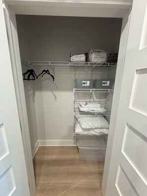 A closet with shelves, hanging space, and a storage bin.