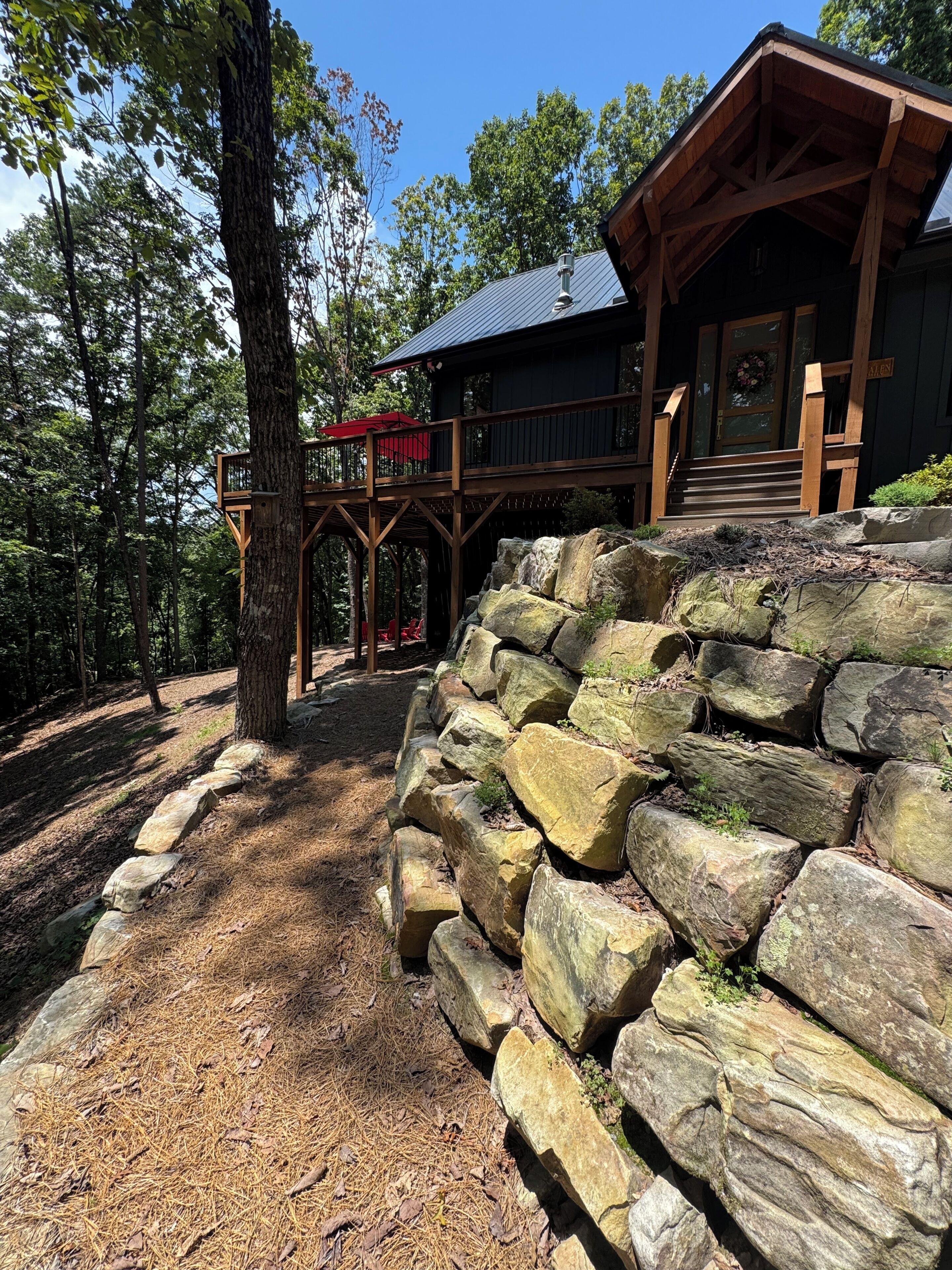 Une cabane dotée d’une terrasse en bois et d’un mur de soutènement en pierre.