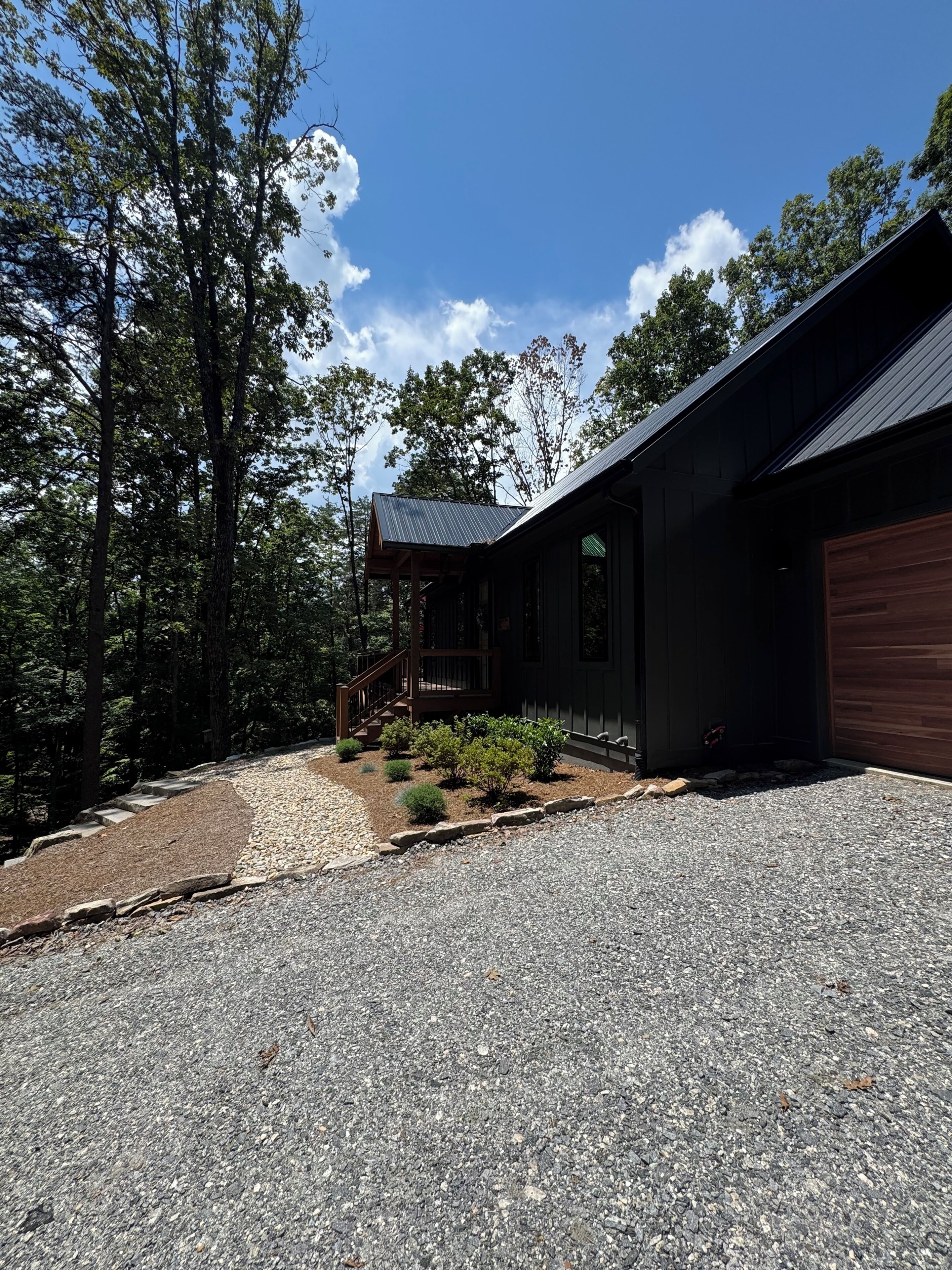 A modern house with a gravel driveway, a wooden deck, and a garage.