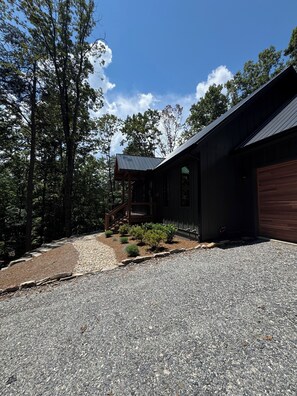 A modern house with a gravel driveway, a wooden deck, and a garage.