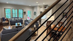 Un salon moderne avec un escalier, un plancher en bois et un coin repas comprenant une table et des chaises.