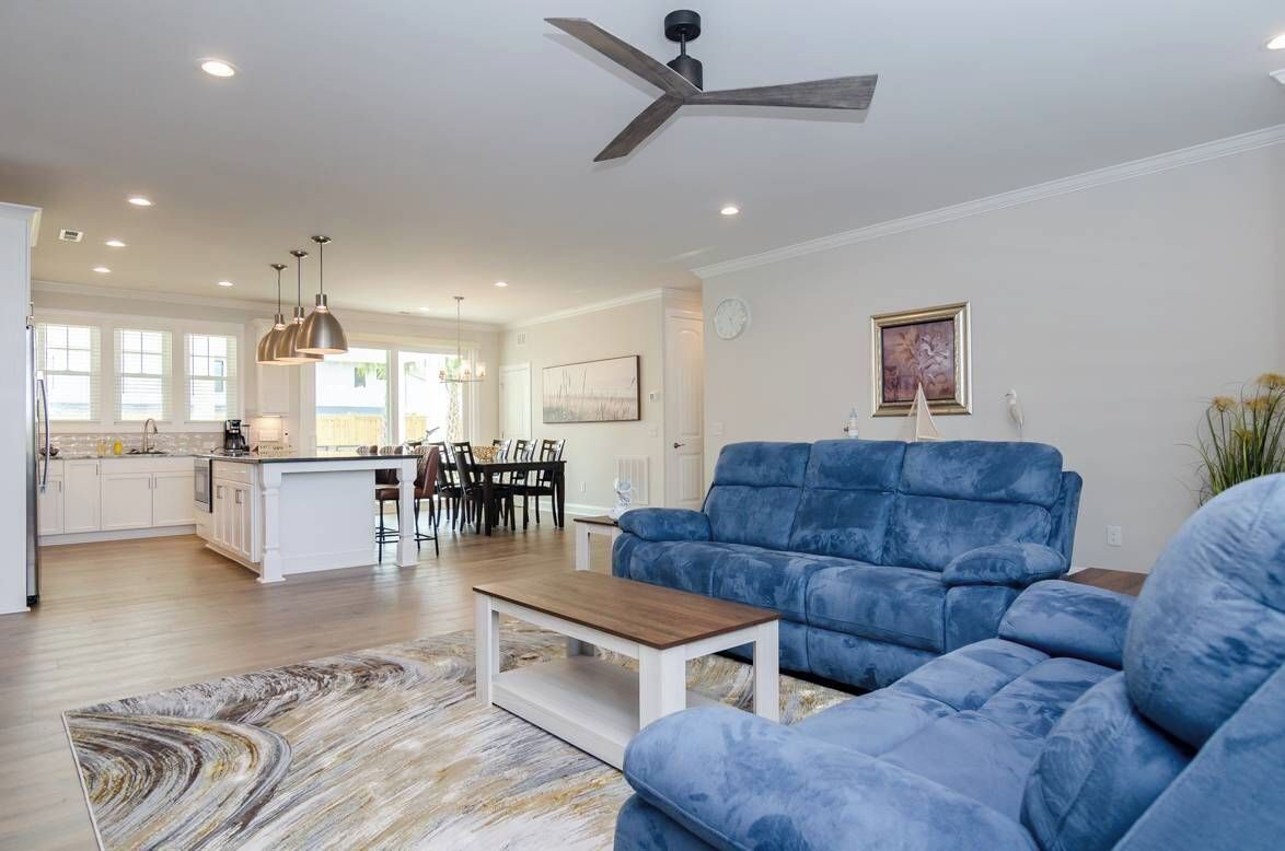A spacious living area with a blue sofa, a wooden coffee table, and a ceiling fan.