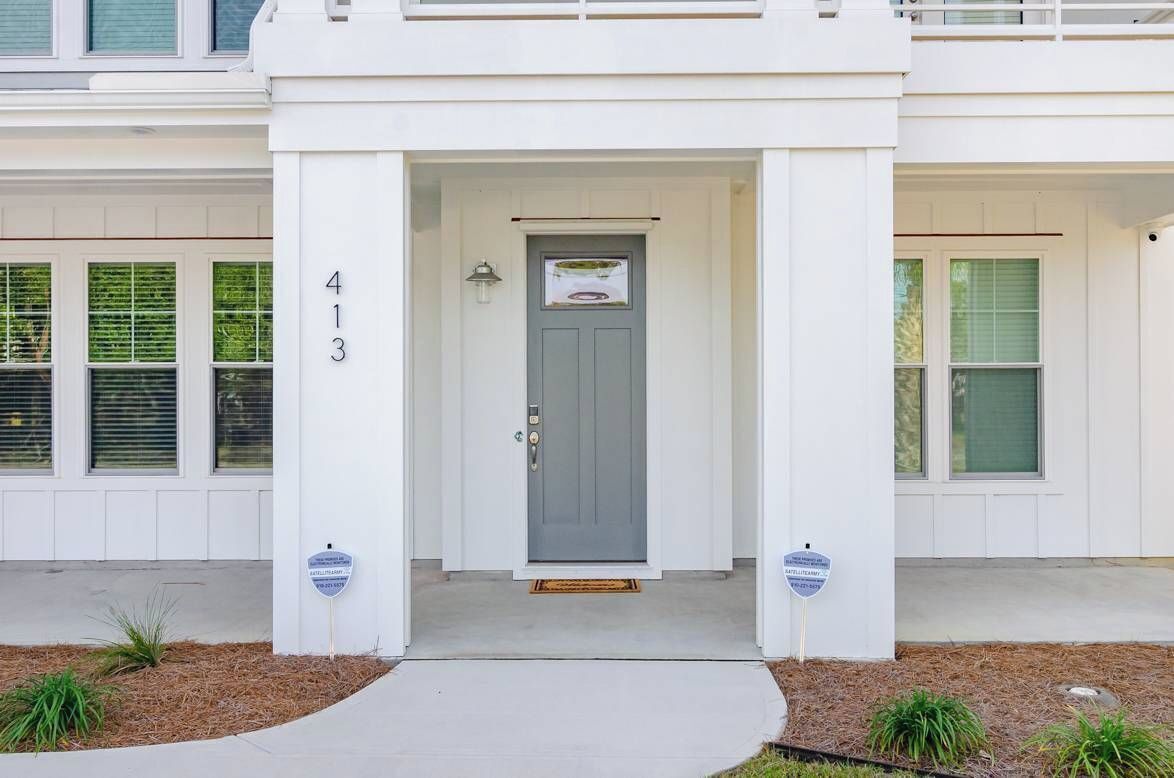 A white building with a gray front door, number 413, and two blue signs on either side of the entrance.