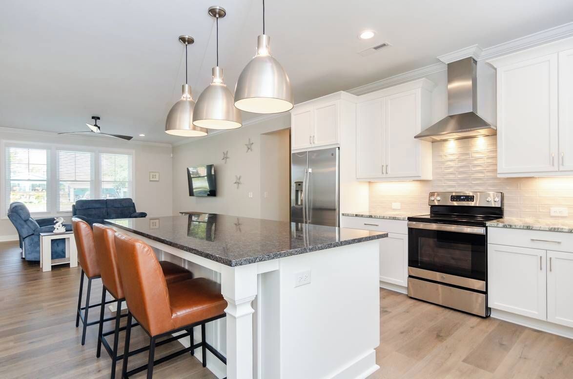 A modern kitchen with white cabinets, stainless steel appliances, and pendant lighting.