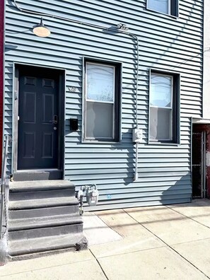A two-story building with a dark front door, two windows, and a visible electrical meter. - Family Fun Retreat Game Room 4BR & Outdoor Oasis (Camden)