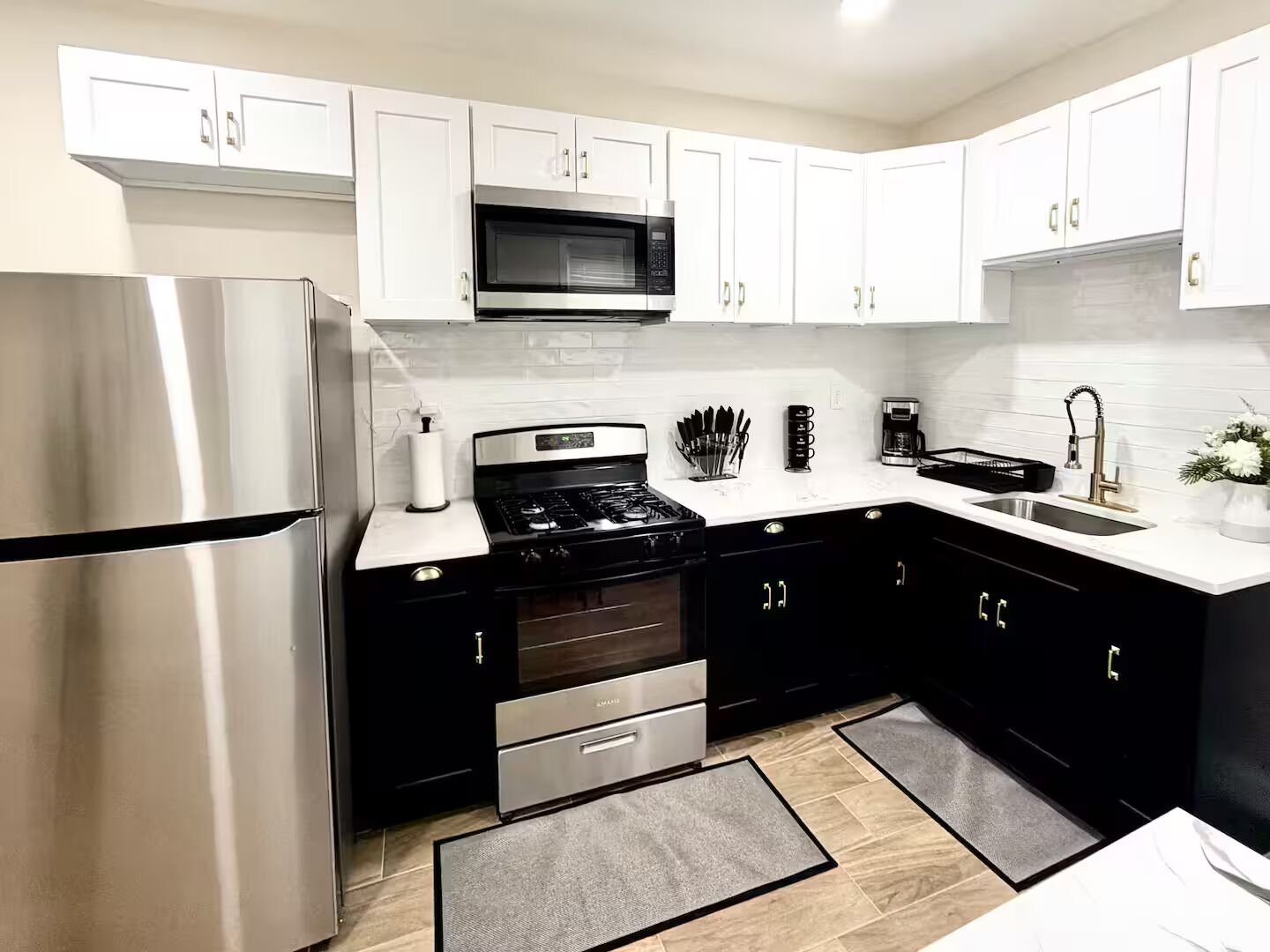 A modern kitchen with white cabinets, stainless steel appliances, and a black countertop.