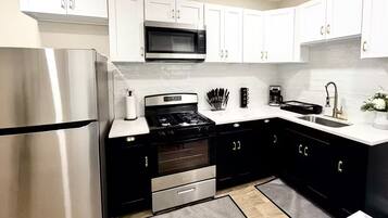 A modern kitchen with white cabinets, stainless steel appliances, and a black countertop.