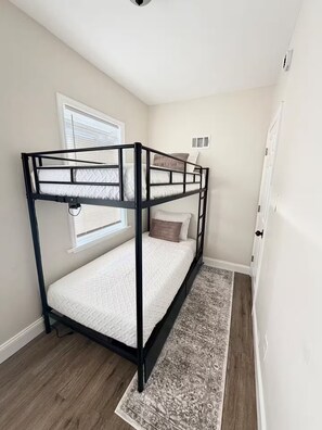 A bunk bed with a headboard, a window with blinds, a door, and a patterned rug. - Family Fun Retreat Game Room 4BR & Outdoor Oasis (Camden)