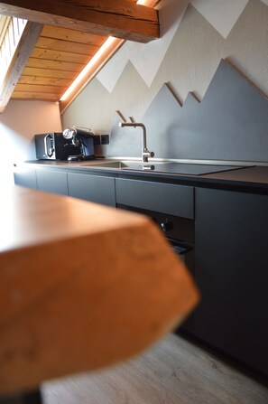 A modern kitchen with a built-in coffee maker, a sink, and a wooden table. - Mountain Suite apartment with a sauna and an open-plan bathtub (Sanzeno)