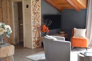 A modern living room with a fireplace, a television, and seating arrangements. - Mountain Suite apartment with a sauna and an open-plan bathtub (Sanzeno)