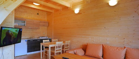 A wooden interior with a kitchenette, a dining area, and a sofa.
