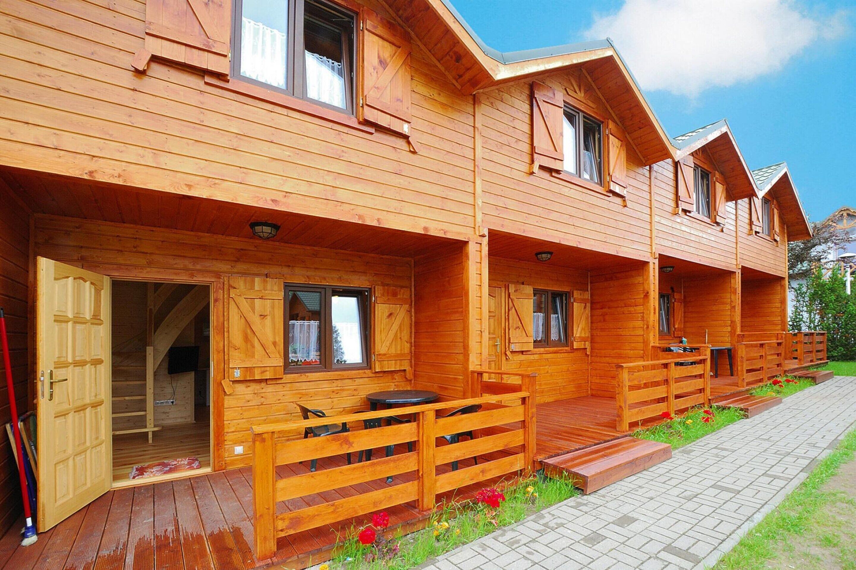 Una cabaña de madera con varias habitaciones, cada una con un ventanal y un porche pequeño.