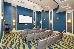 A conference room with rows of chairs, a large screen, and a podium. - 9BR Resort Home for Large Groups with Private Pool Near Disney (Four Corners)