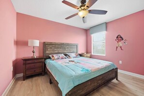 A bedroom with a bed, nightstand, lamp, ceiling fan, and a window with blinds. - 9BR Resort Home for Large Groups with Private Pool Near Disney (Four Corners)