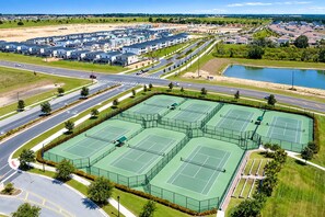 A residential area with multiple tennis courts, a road, and a body of water. - 9BR Resort Home for Large Groups with Private Pool Near Disney (Four Corners)