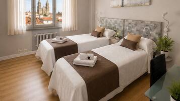 Quarto de hotel com duas camas, vista para a cidade, radiador e mesa com uma planta.