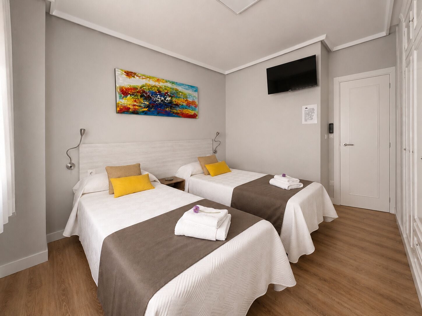 Una habitación de hotel con dos camas, un televisor de pantalla plana y un cuadro en la pared.