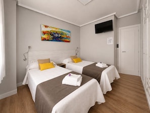 A hotel room with two beds, a flat-screen TV, and a painting on the wall.