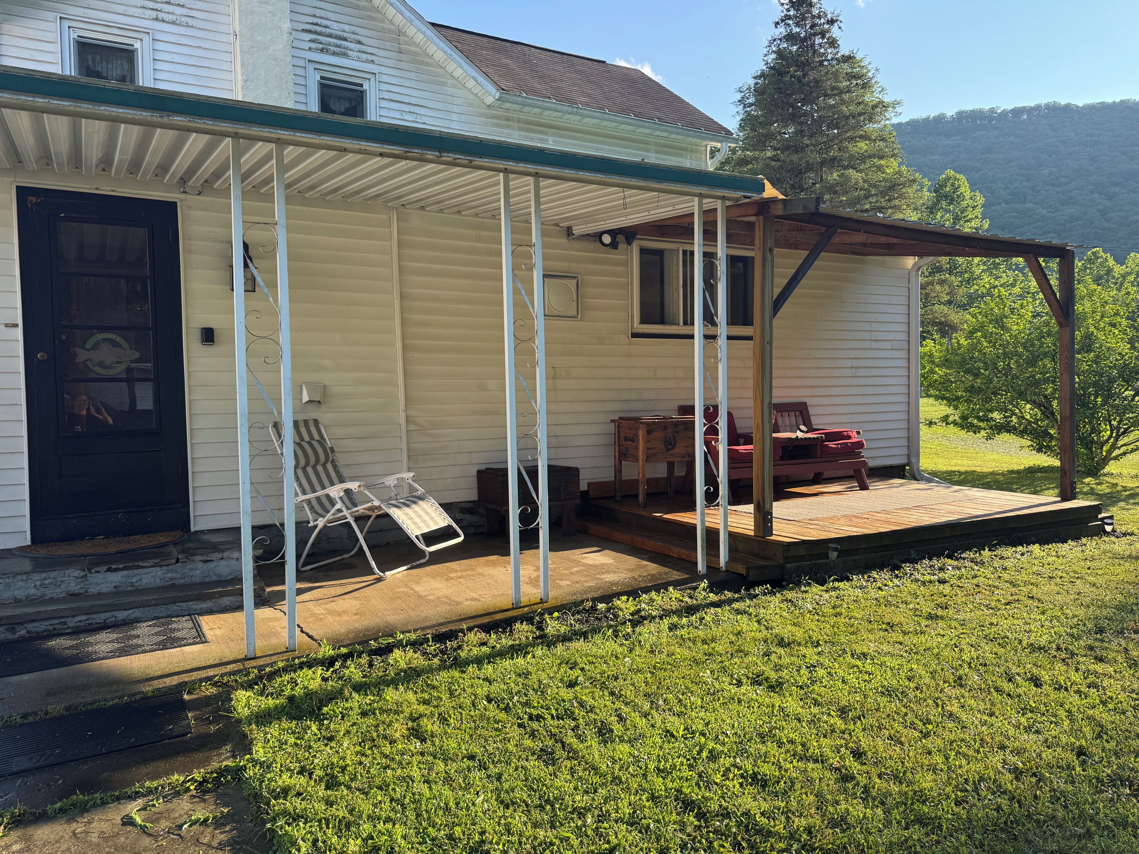 A single-story house with a covered porch, a front door, and a small deck.