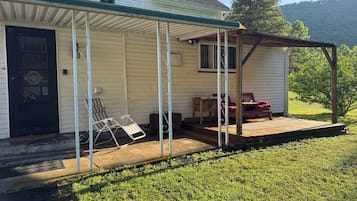 A single-story house with a covered porch, a front door, and a small deck.