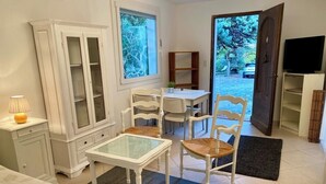 Ein Zimmer mit Bett, Tisch mit Stühlen, Schrank, Fernseher und Blick ins Freie.