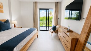 Ett hotellrum med en säng, ett skrivbord, en stol, en tv och en skjutdörr i glas som leder ut till en balkong.