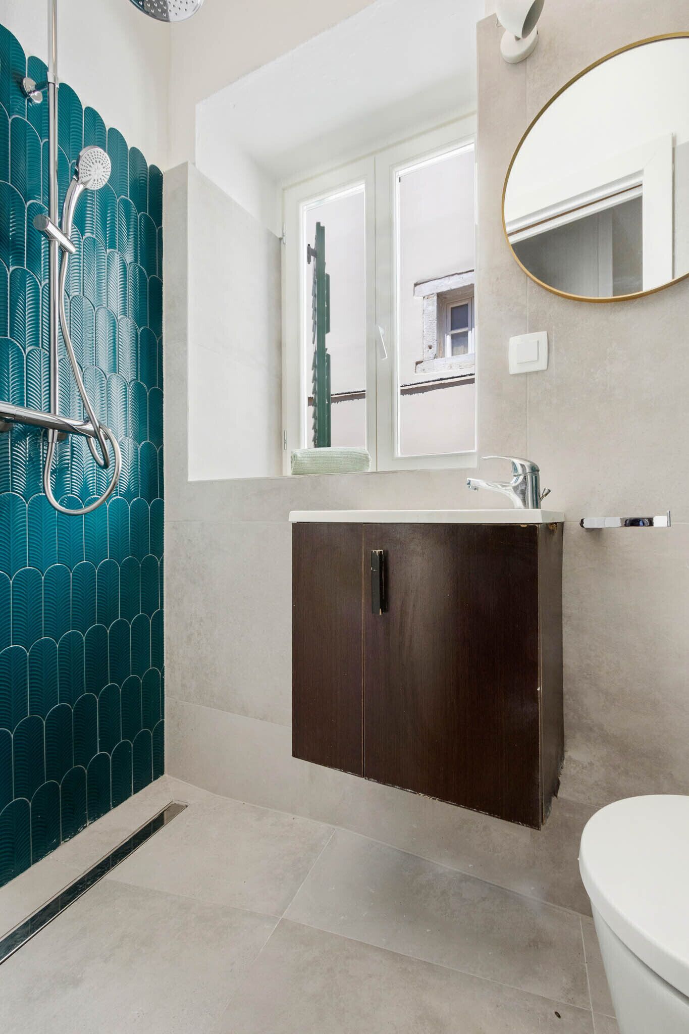 A bathroom with a shower, a sink, a mirror, and a toilet.