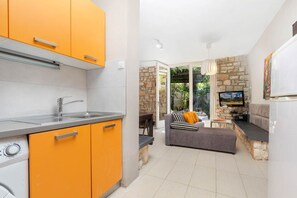 Une cuisine moderne avec des meubles de couleur orange et un coin repas comprenant un canapé et une table.