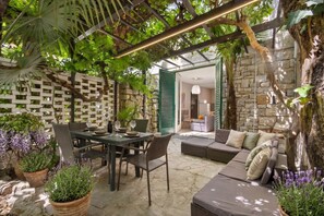 Ein Außenbereich mit Terrasse, einem Esstisch, Stühlen und einer Sofagarnitur.