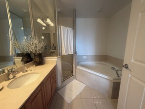 Une salle de bain moderne avec un double vasque, un grand miroir, une baignoire et un espace douche.