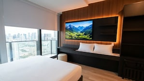 Une chambre d’hôtel moderne dotée d’un grand lit, d’une vue sur la ville, d’un téléviseur fixé au mur et d’un mur d’accent en bois.